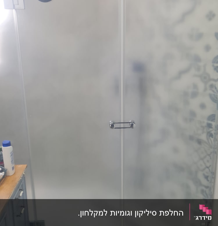 מקלחון זכוכית עם ראש מקלחת ומגבת תלויה